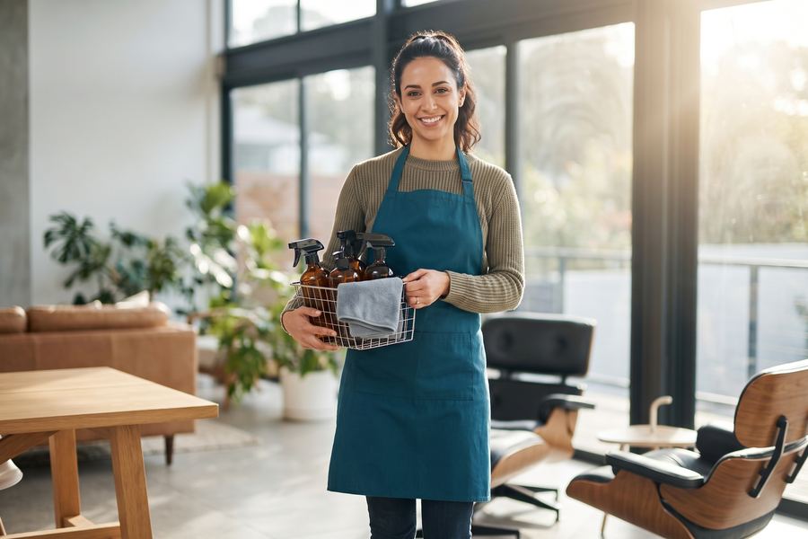 Dona de empresa de limpeza sorrindo em casa moderna e clara
